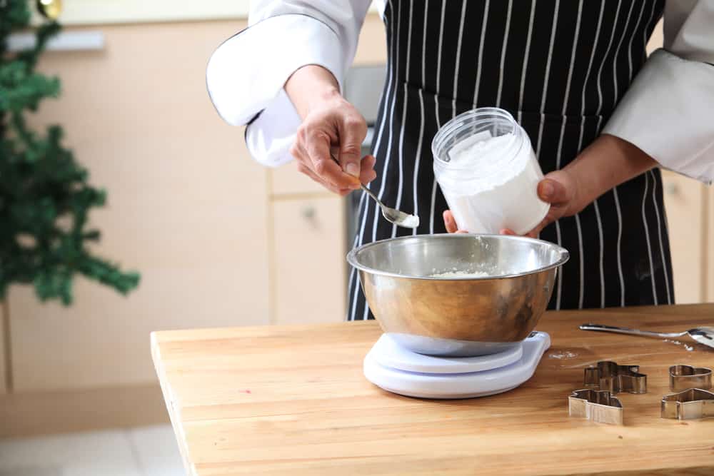 Measuring baking powder into a bowl.