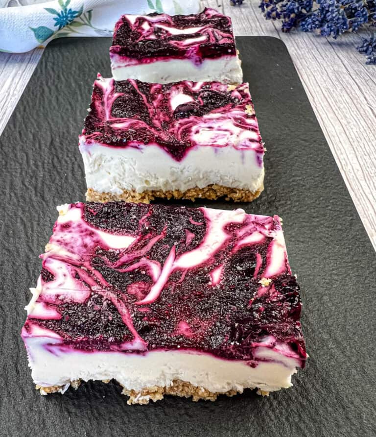 Pieces of No-Bake Blueberry Cheesecake Bars on a slate plate.