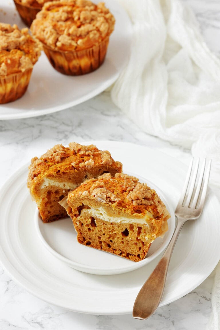 A plate of Cinnamon Cream Cheese Pumpkin Muffins with other muffins on the background.