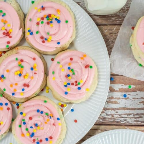 Pink frosted sugar cookies on white plates.