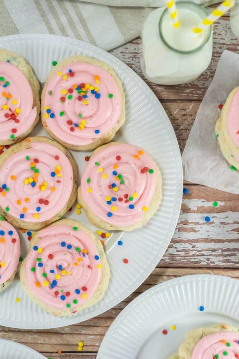 Pink frosted sugar cookies on white plates.