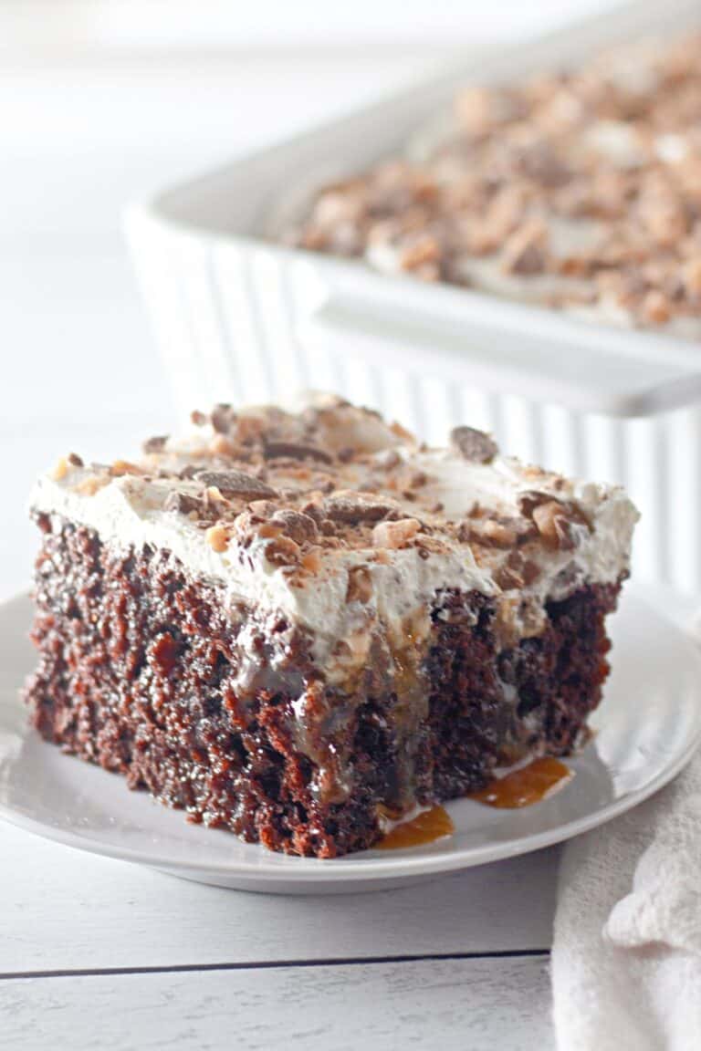 A slice of Heath Bar Poke Cake on a white plate.