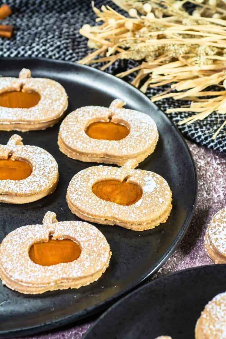 Pumpkin Linzer Cookies on a black round plate.