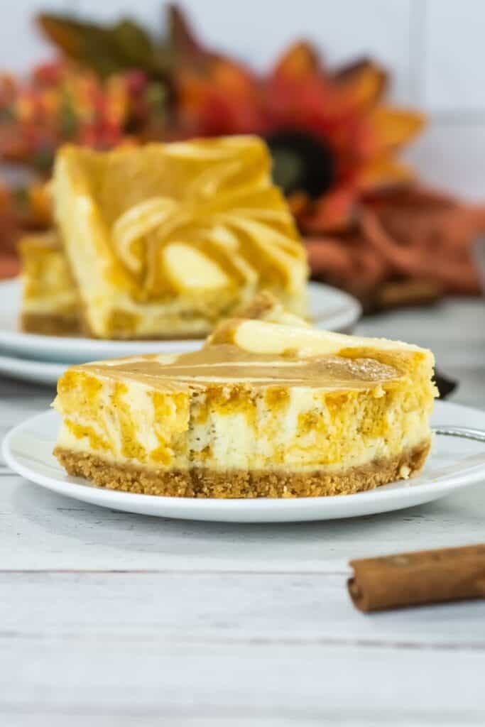 A small white plate holds a slice of pumpkin cheesecake bars.