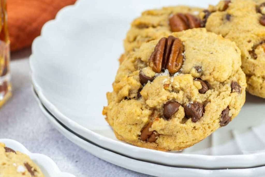 Closeup shot of browned butter bourbon pecan chocolate chip cookies on a plate.